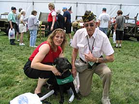 Marikay and Cynthia squatting with a WW2 veteran at the festivities