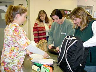 Three women are learning about the stuff in the bag from a staff member.