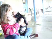 Trish holding a pup while sitting on the floor